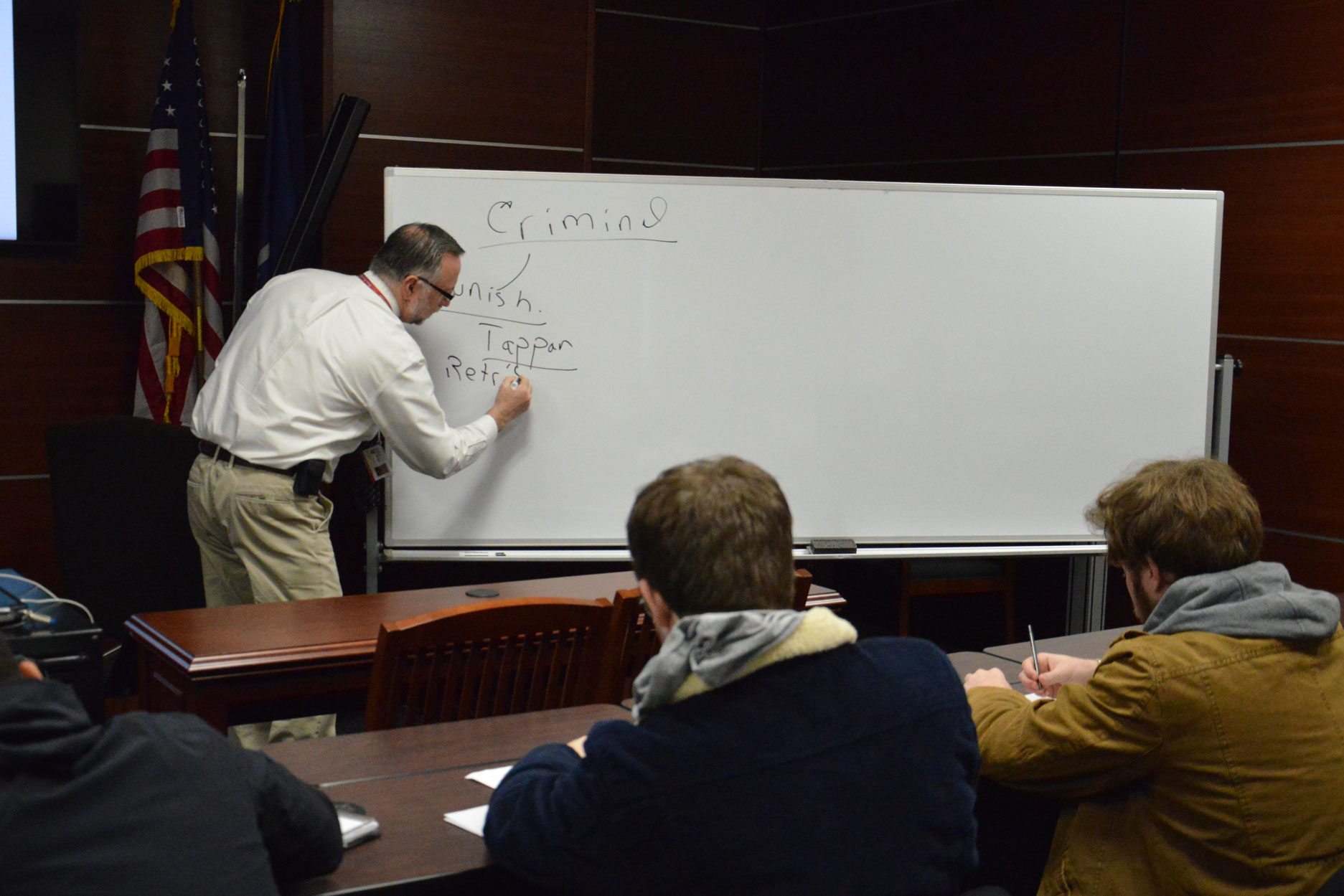 Professor writes on whiteboard for students in Molloy University's Criminal Justice department
