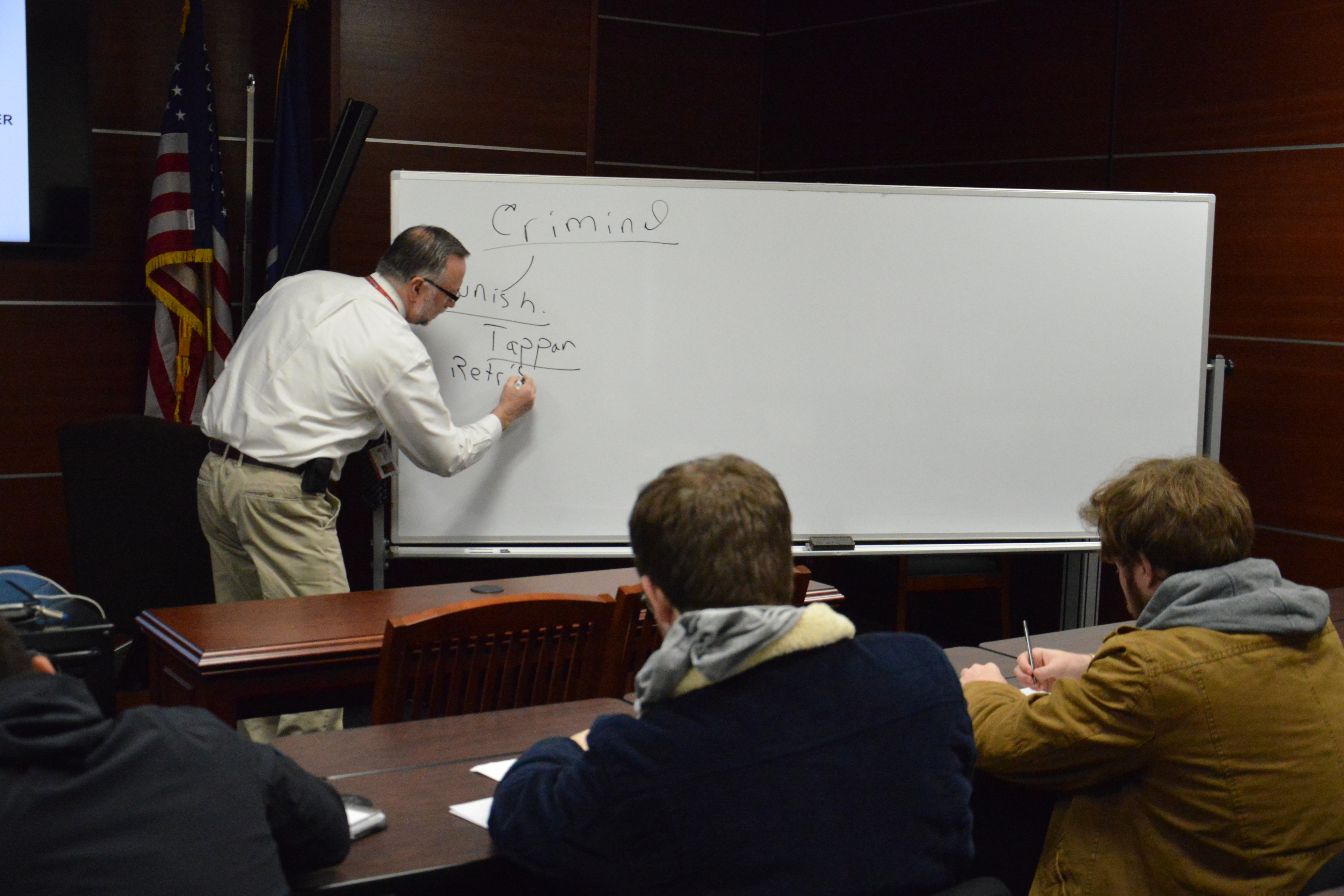 Professor writes on whiteboard for students in Molloy University's Criminal Justice department
